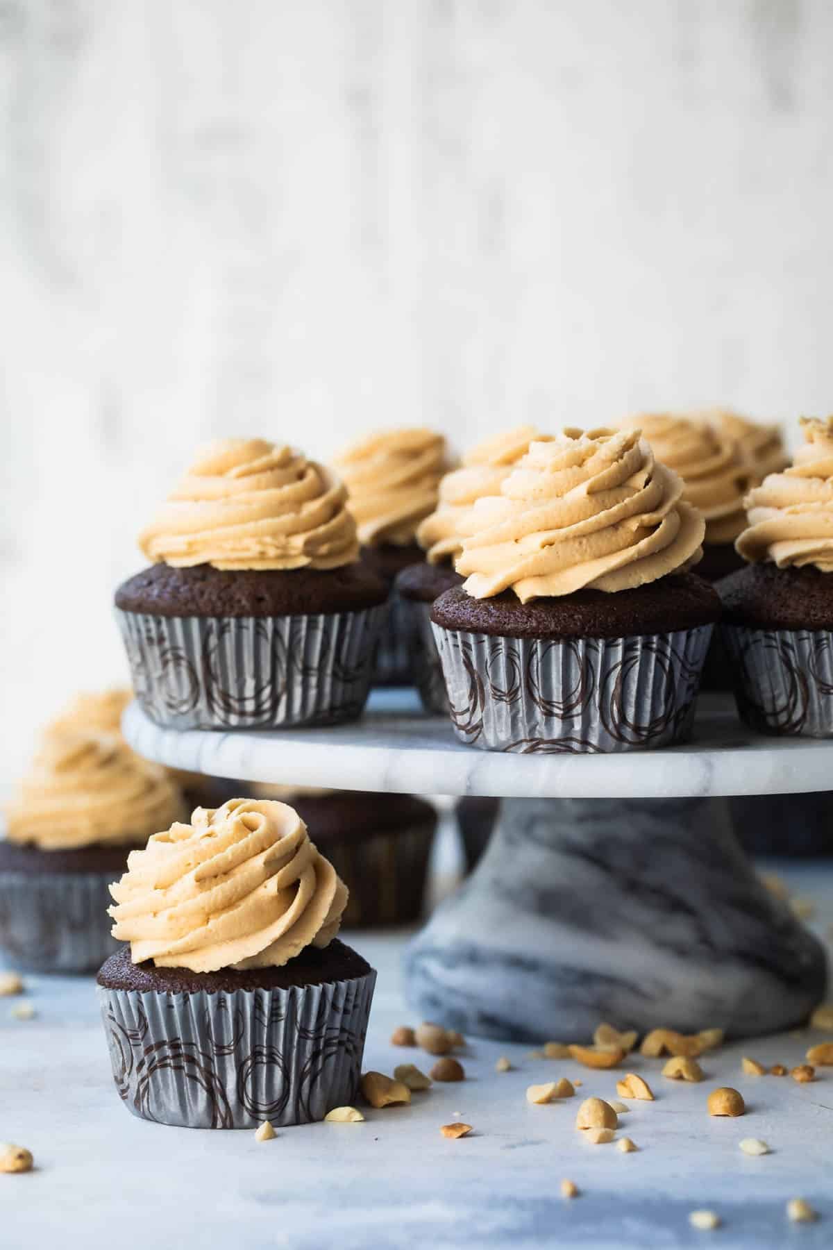 A cake stand filled with chocolate cupcakes with peanut butter frosting.
