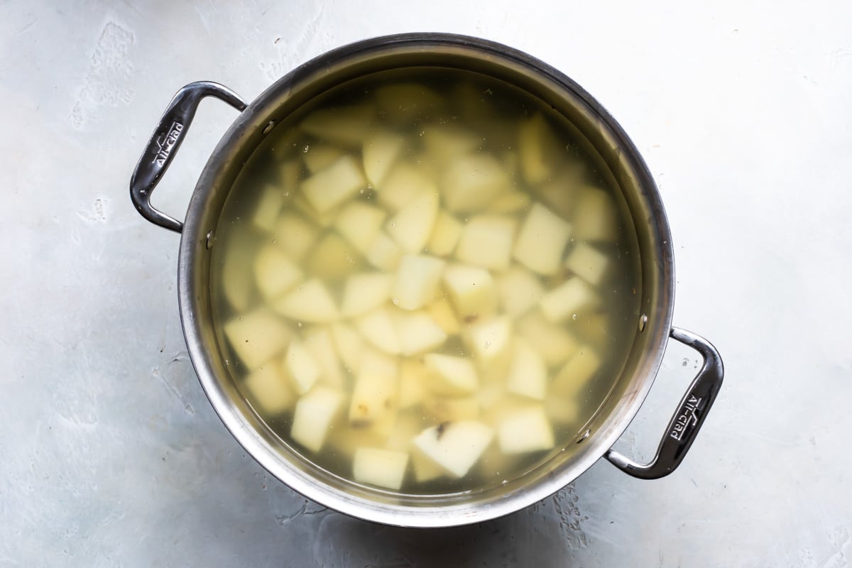 Potatoes being boiled in a silver pot.