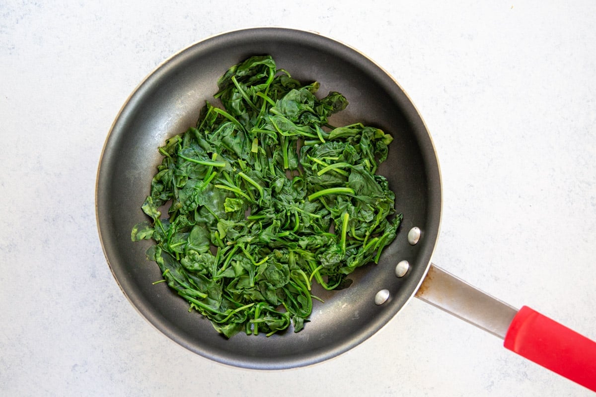 Spinach wilted in a skillet.