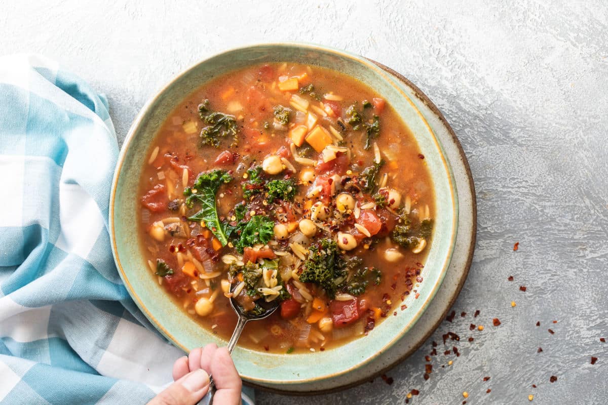 Minestrone soup in a teal bowl.