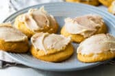 Frosted pumpkin cookies on a gray plate.