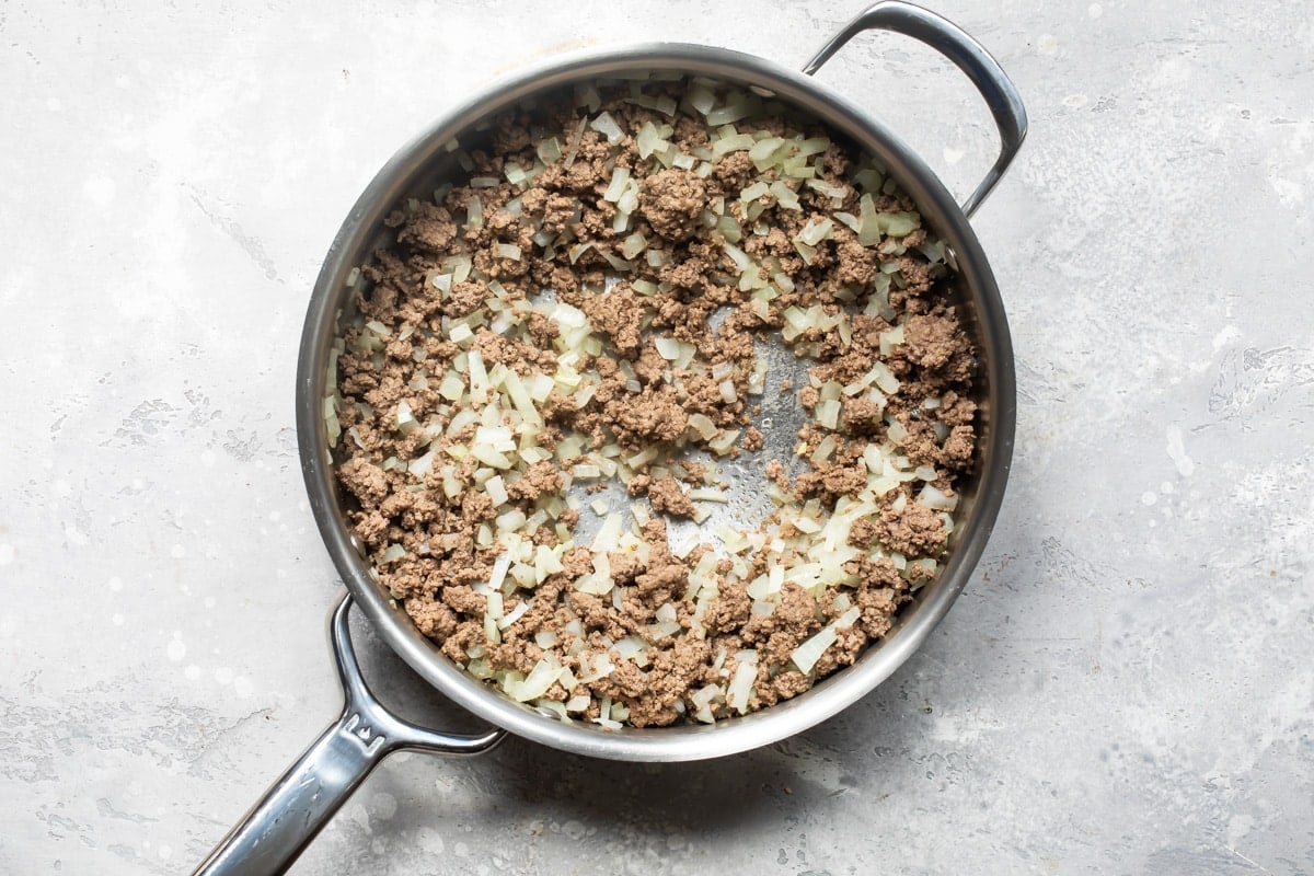 Ground beef and onion cooked in a saucepan.