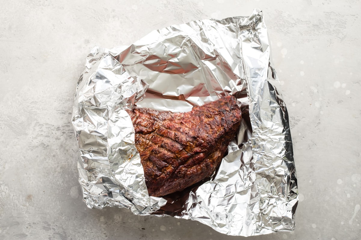An overhead shot of smoked tri tip wrapped in tin foil.