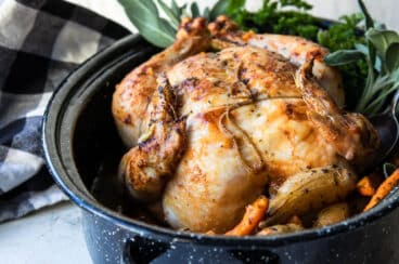 A whole roasted chicken in a graniteware pan.