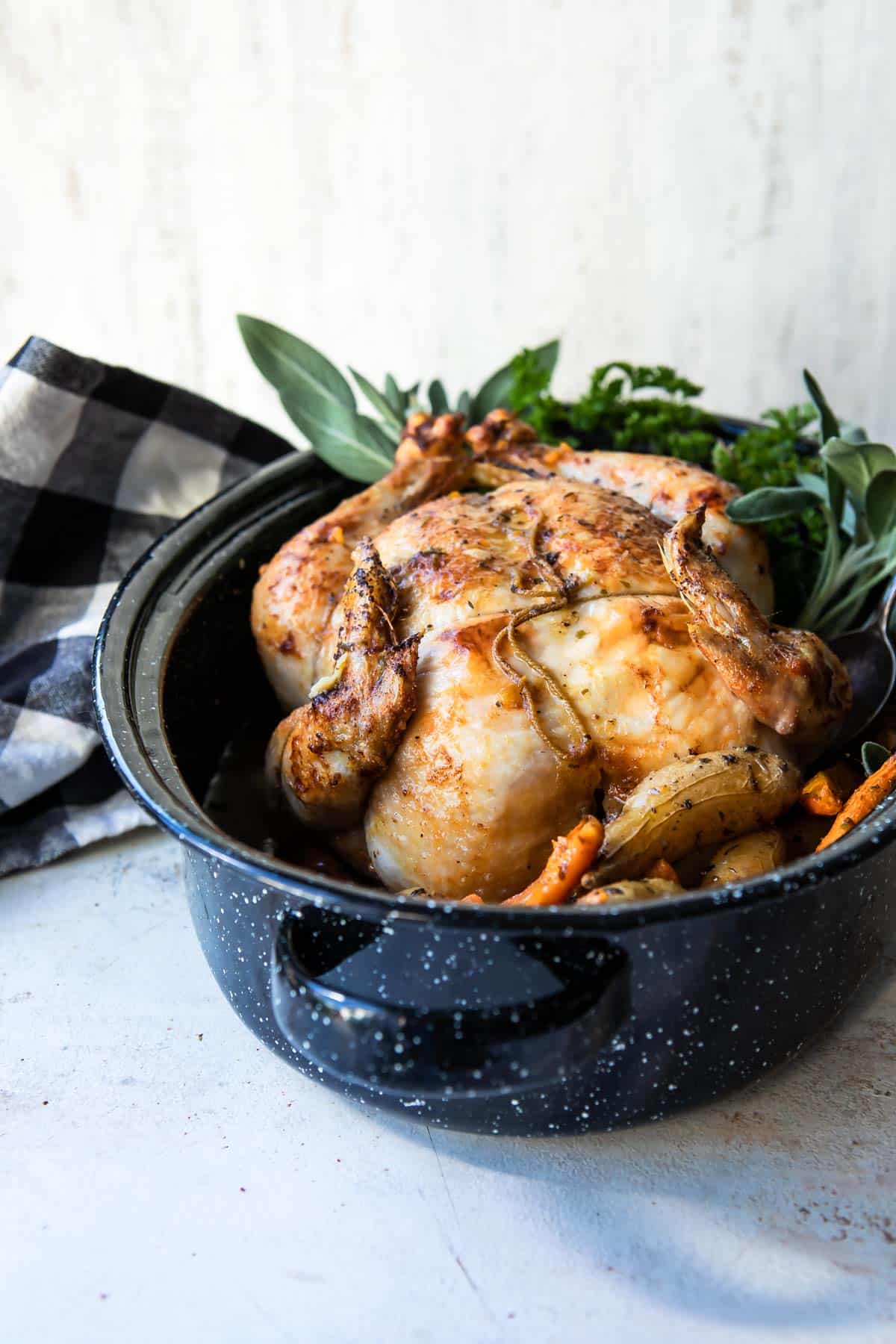 A whole roasted chicken in a graniteware pan.