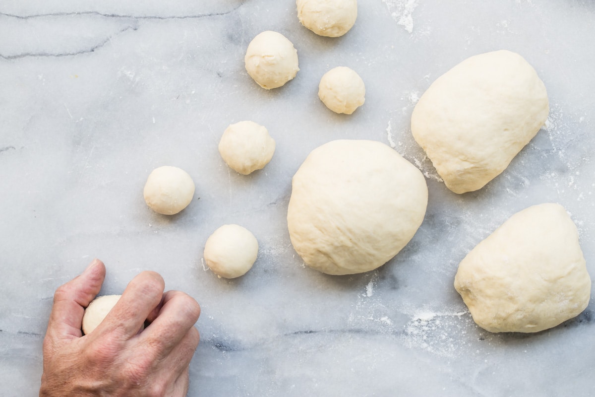 Rolling balls of dough for dinner rolls.