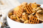 A bowl of Chex mix on a gray background.