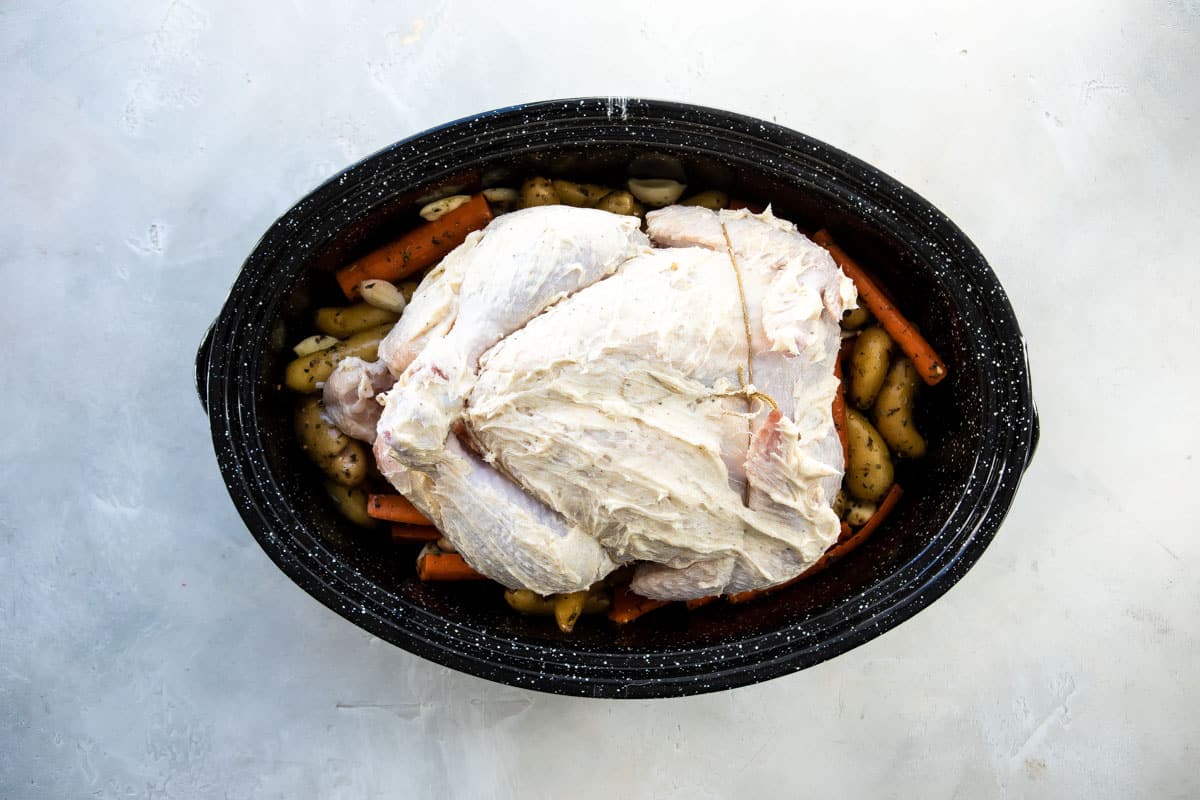 A garlic butter chicken and vegetables in a roasting pan before being baked.