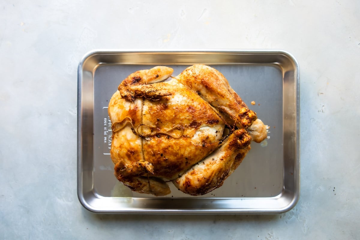 A whole chicken trussed and on a baking sheet.