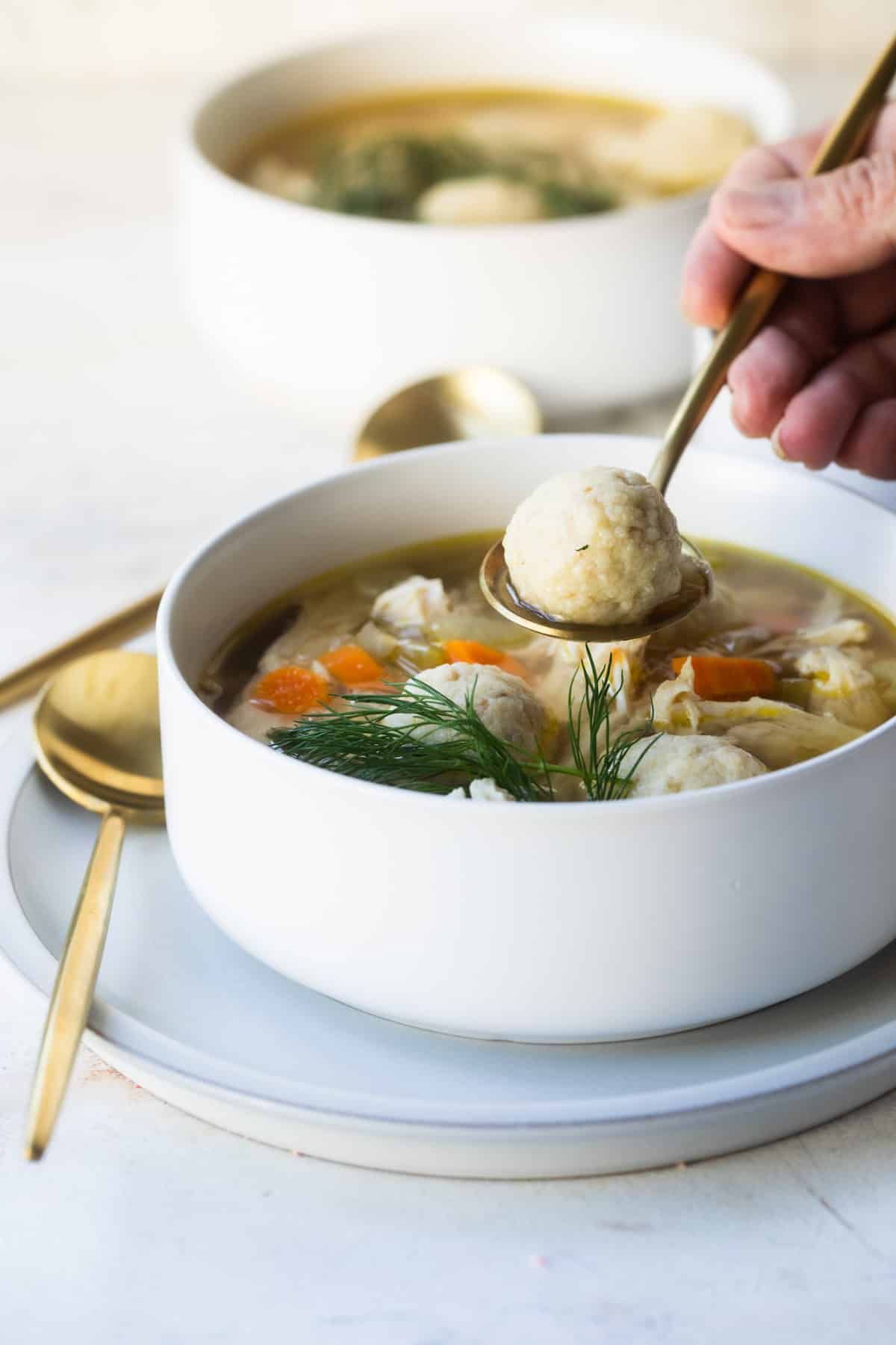 White bowls filled with matzo ball soup.