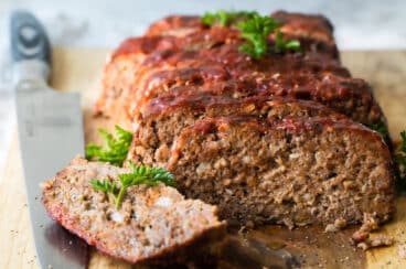 Meatloaf slices on a wooden cutting board.