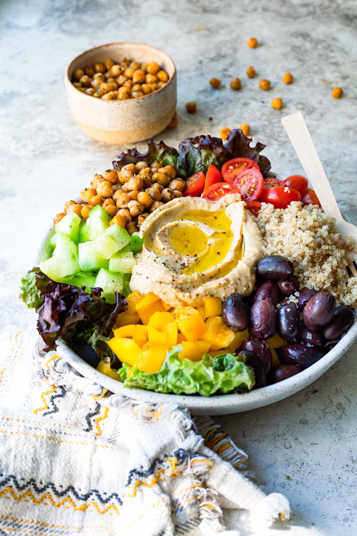 A Mediterranean Buddha bowl next to a small bowl of roasted chickpeas.