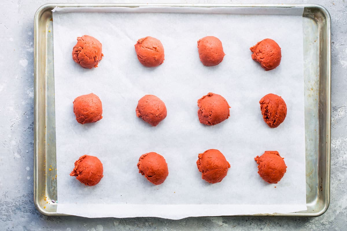 Peppermint cookie dough balls rolled on a baking sheet before baking.