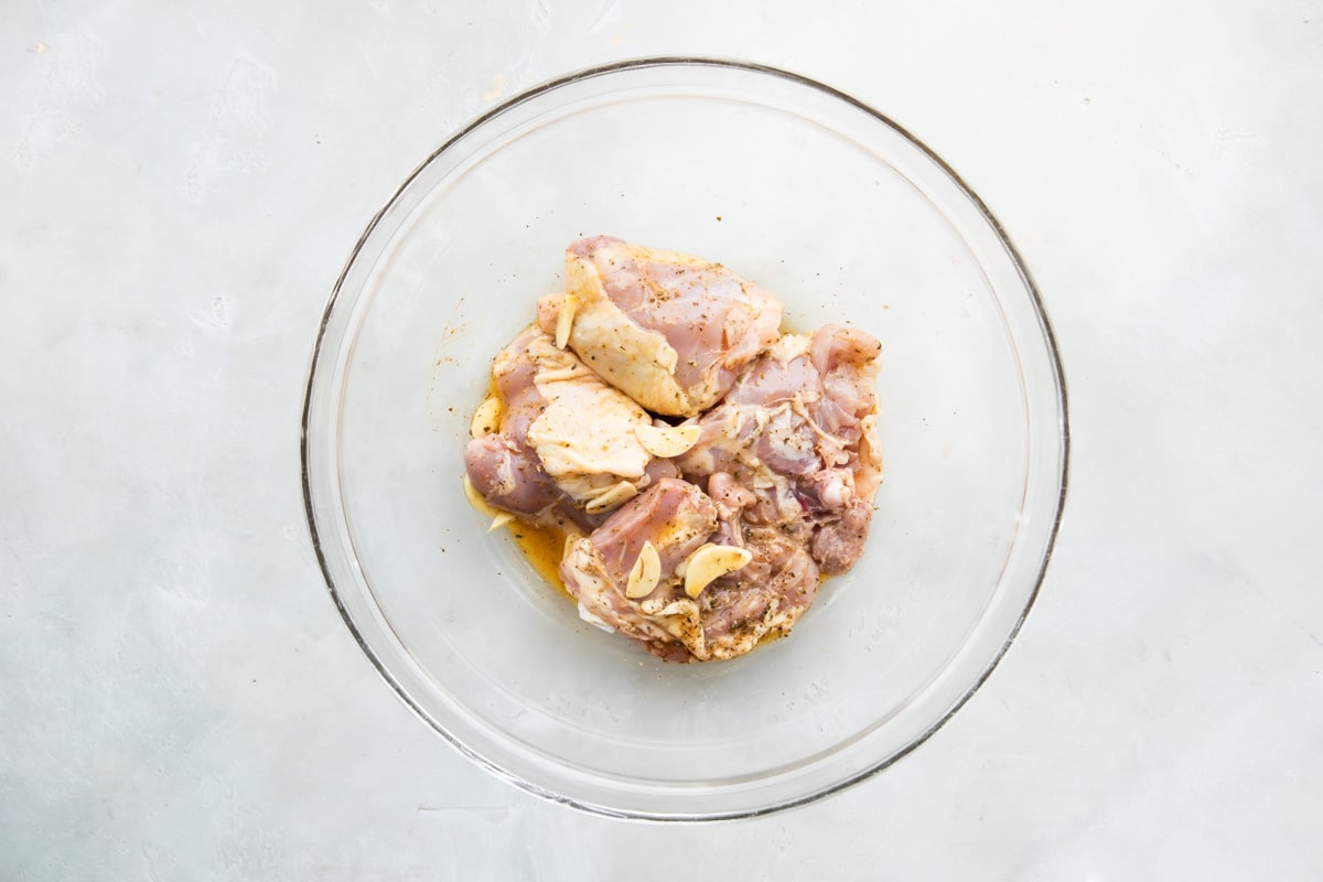Chicken marinating in a clear glass bowl.