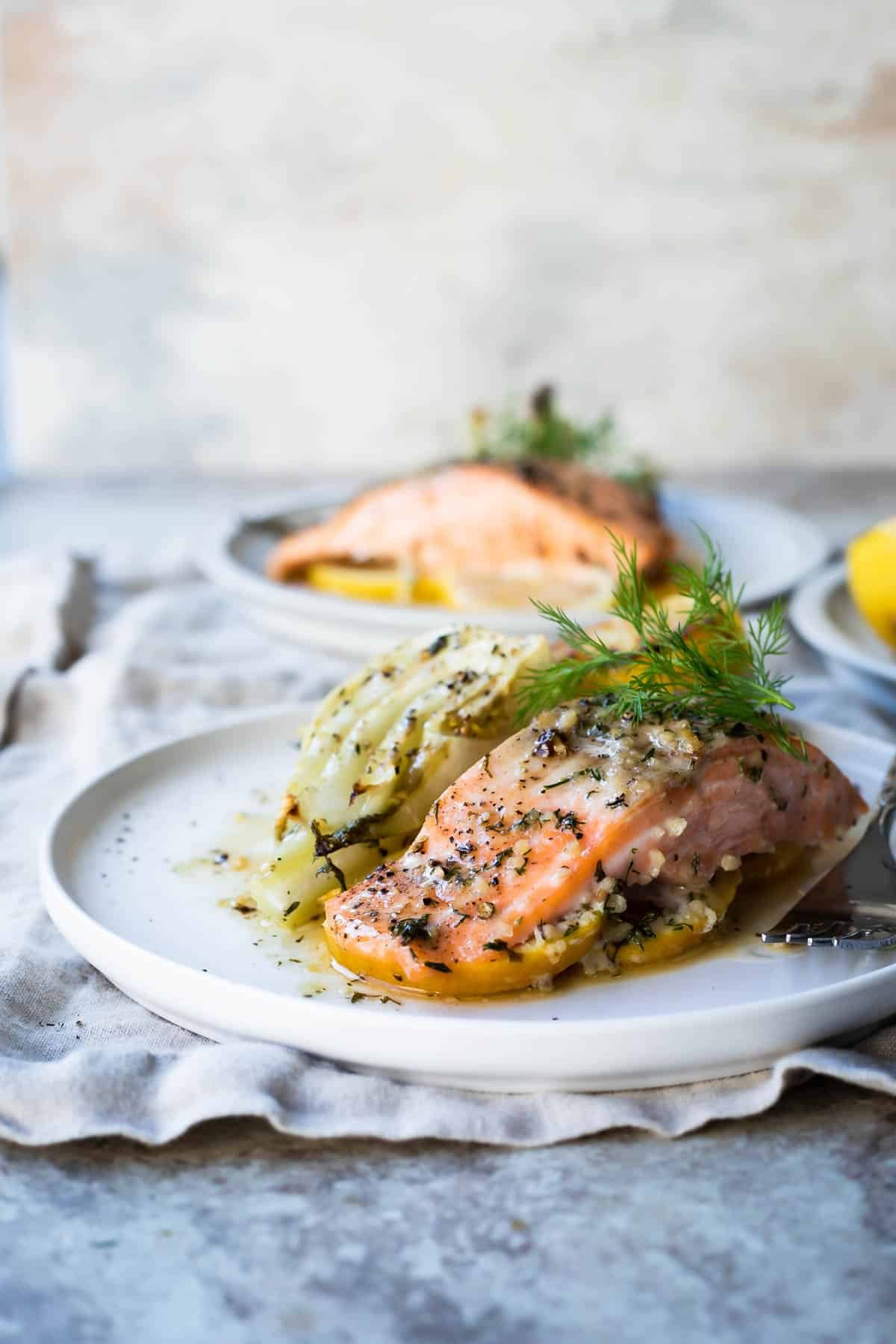 Salmon filets on two plates with roasted fennel.