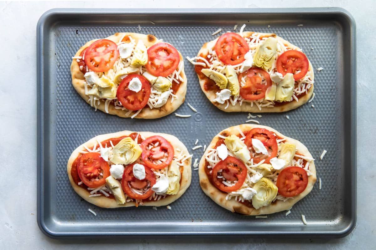 Flatbread pizzas on a baking sheet before baking.