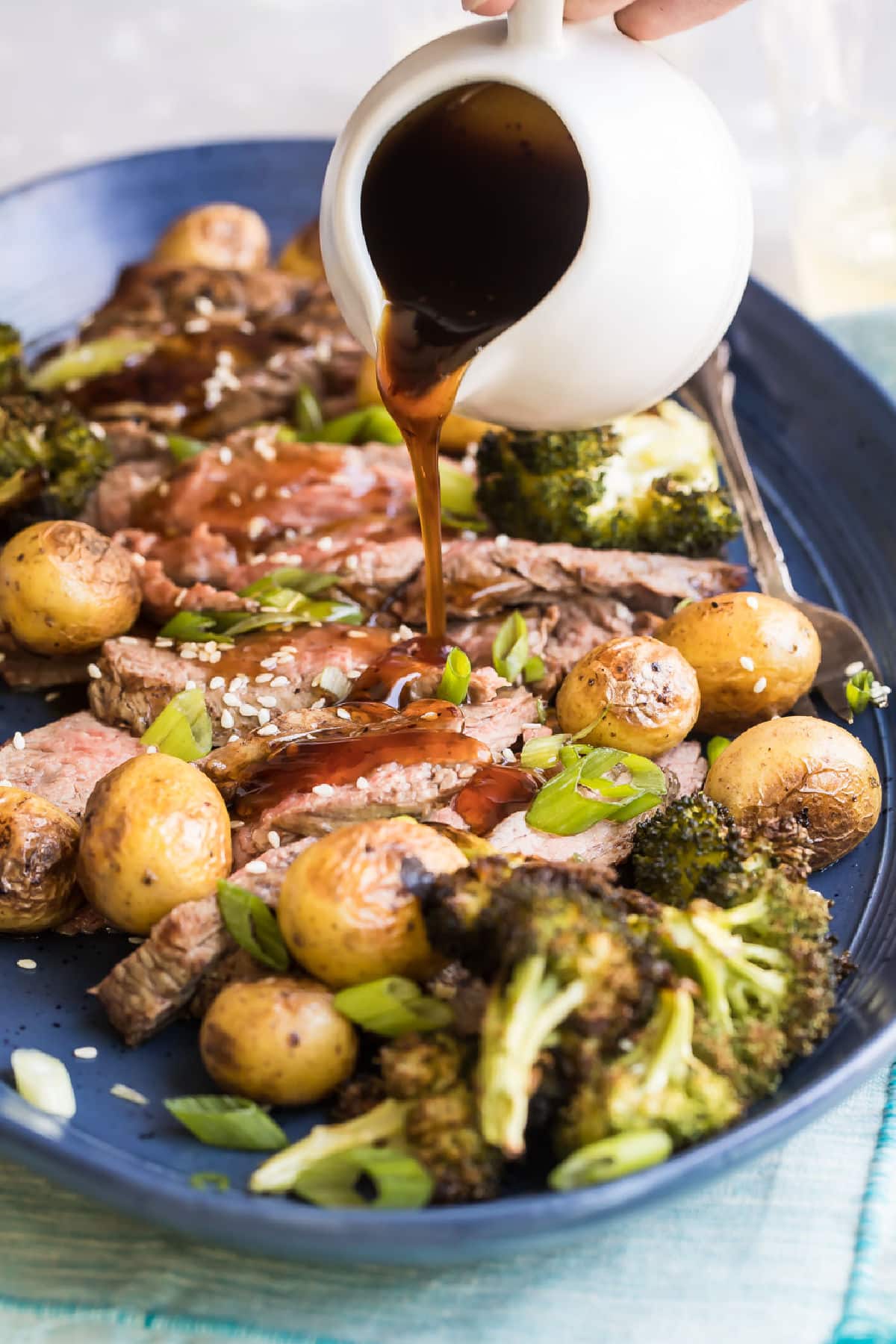 A platter of Hibachi Steak with Grilled Wasabi potatoes and teriyaki sauce being drizzled over it.