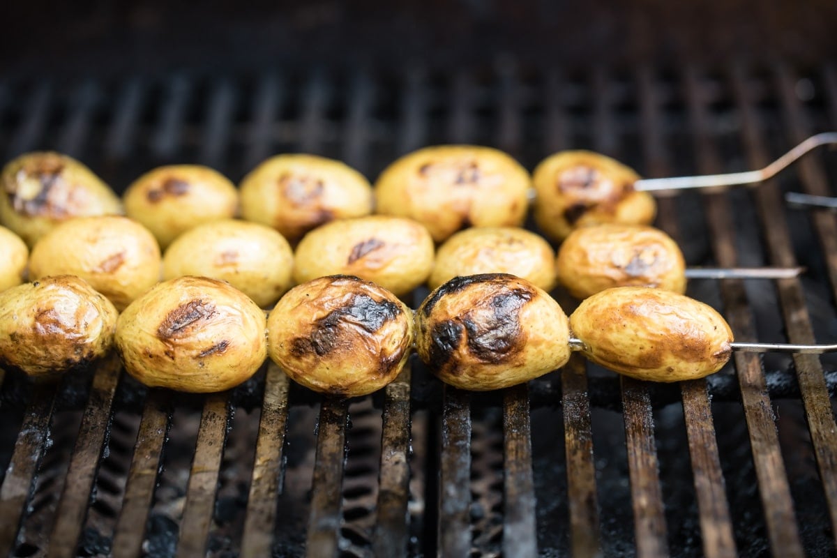 Skewered potatoes on a grill.