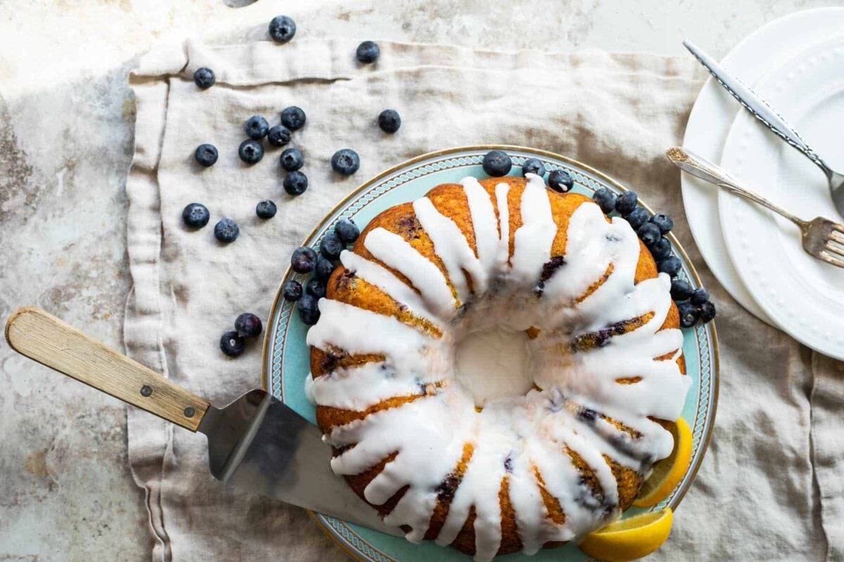 A Lemon Blueberry Cake with glaze on a platter.