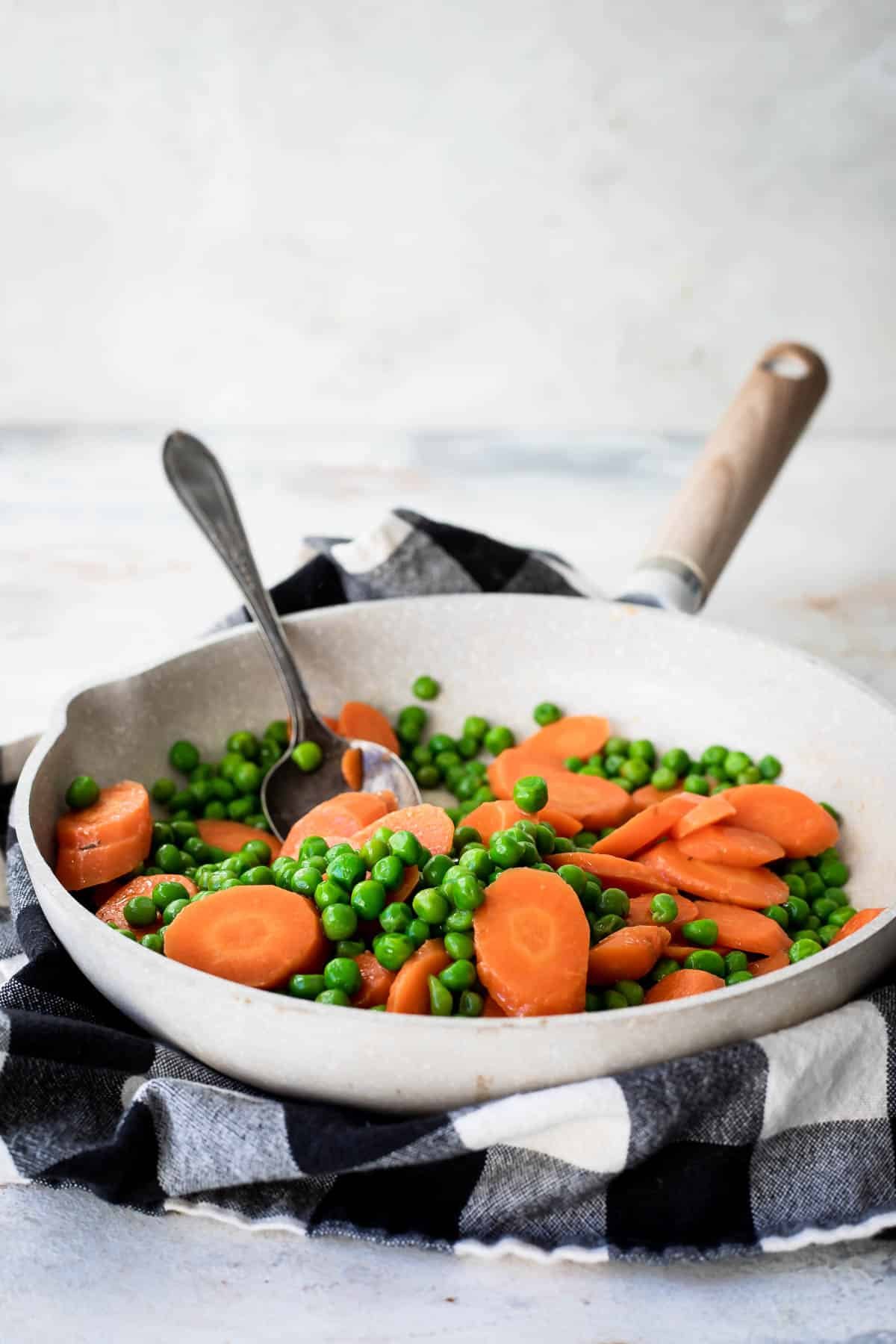 Peas and carrots in a white pan.