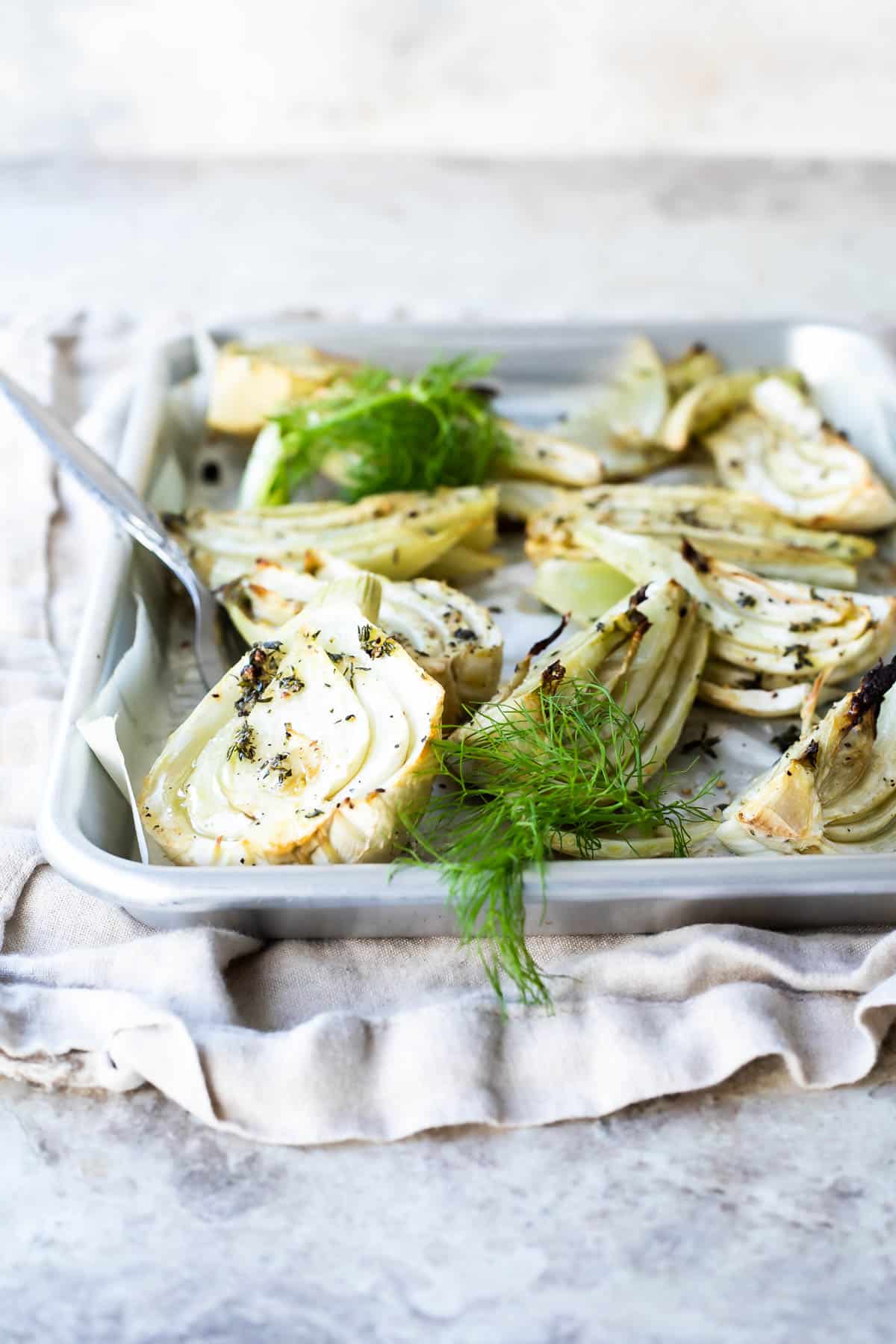 Roasted fennel on a parchment paper lined baking sheet.