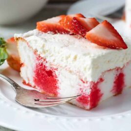 A slice of strawberry jello poke cake on a white plate.