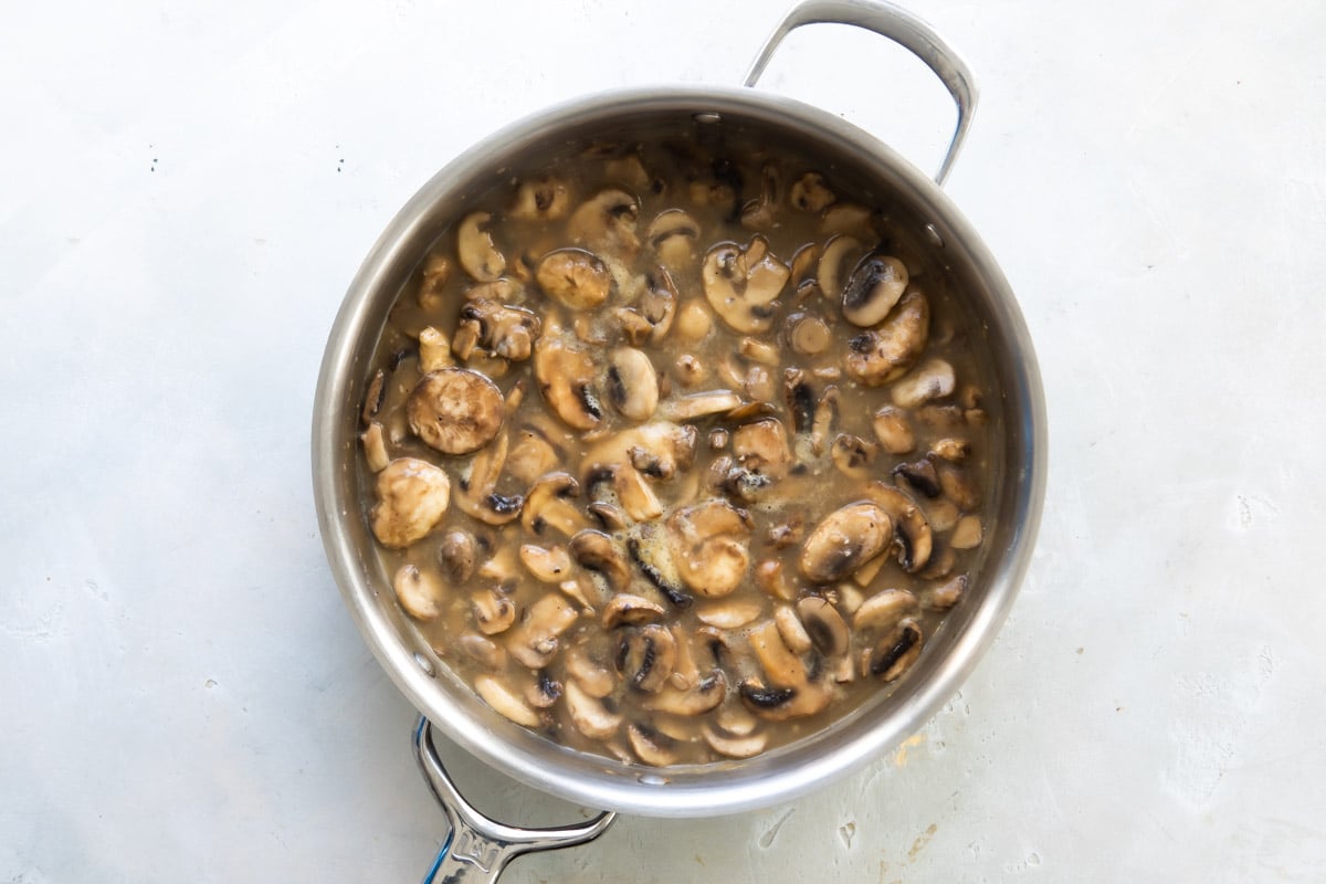 Mushrooms and sauce in a silver skillet.