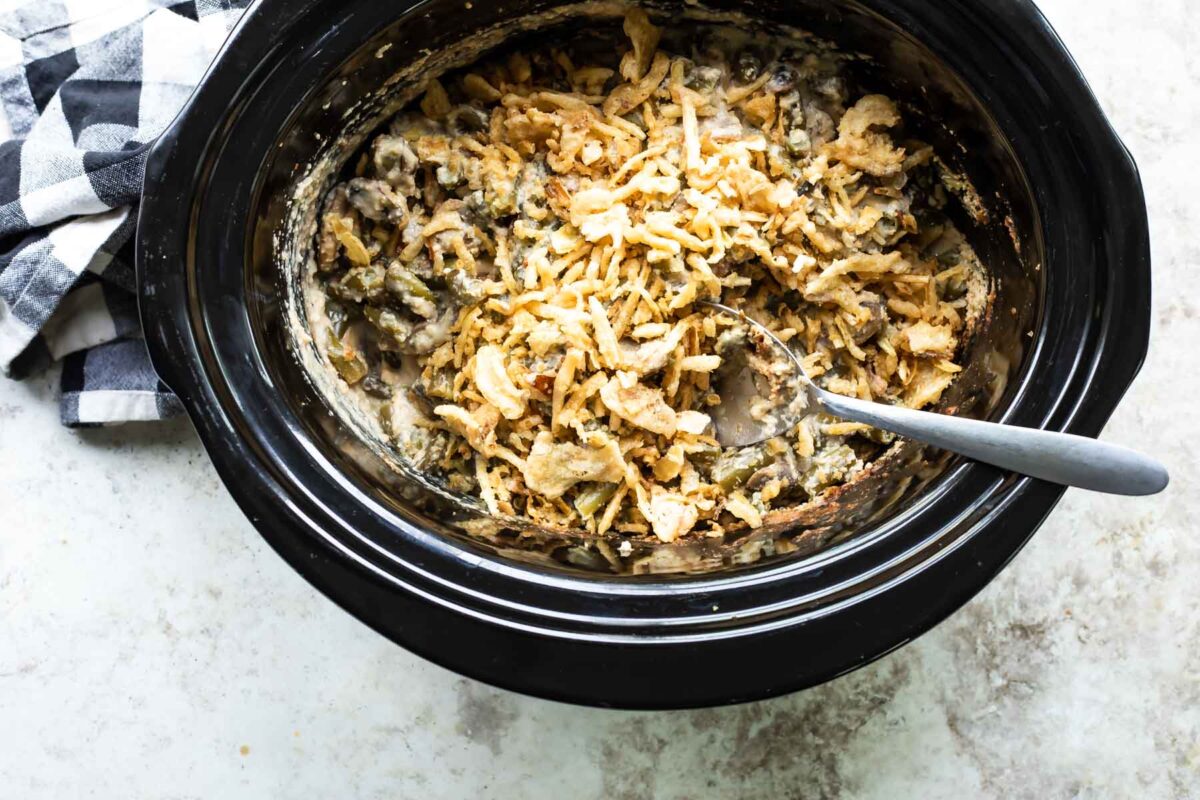 Vegan green bean casserole in a black slow cooker.