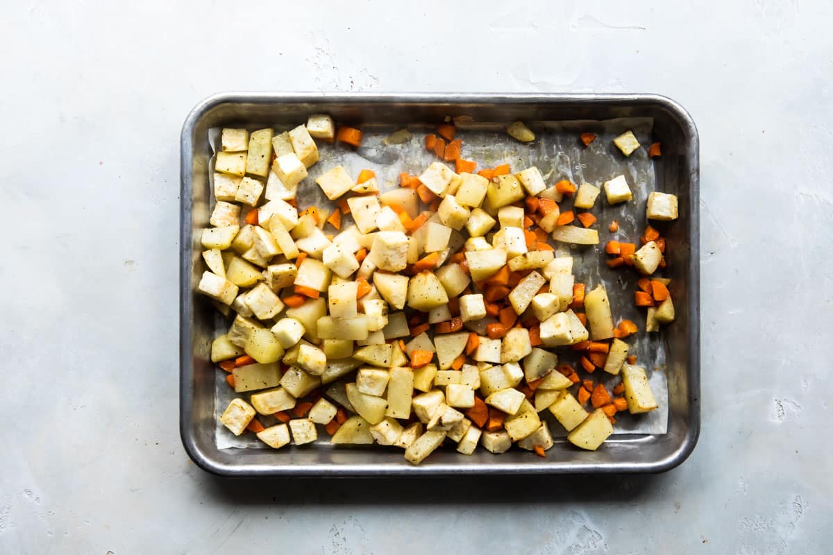 Potatoes and carrots being cooked on a baking sheet for vegetable pot pie.