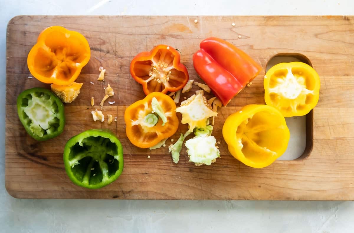 Bell peppers being cut on a wooden cutting board.