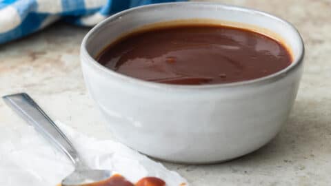 Barbecue sauce in a small gray bowl with a spoon next to it.