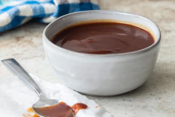 Barbecue sauce in a small gray bowl with a spoon next to it.