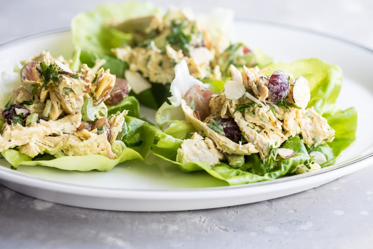 A white plate with lettuce cups filled with curried chicken salad.
