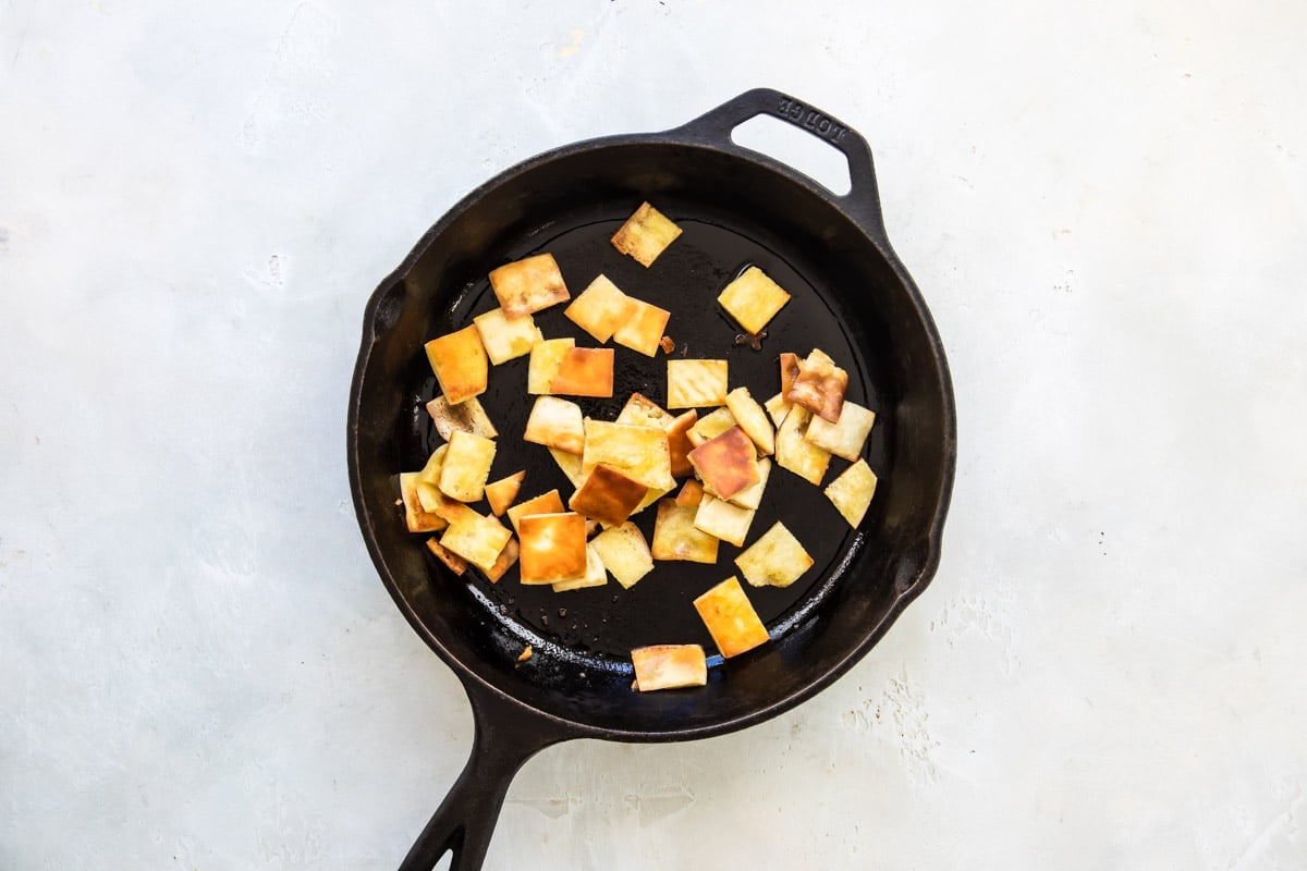 Frying pita bread in a cast iron skillet for fattoush.