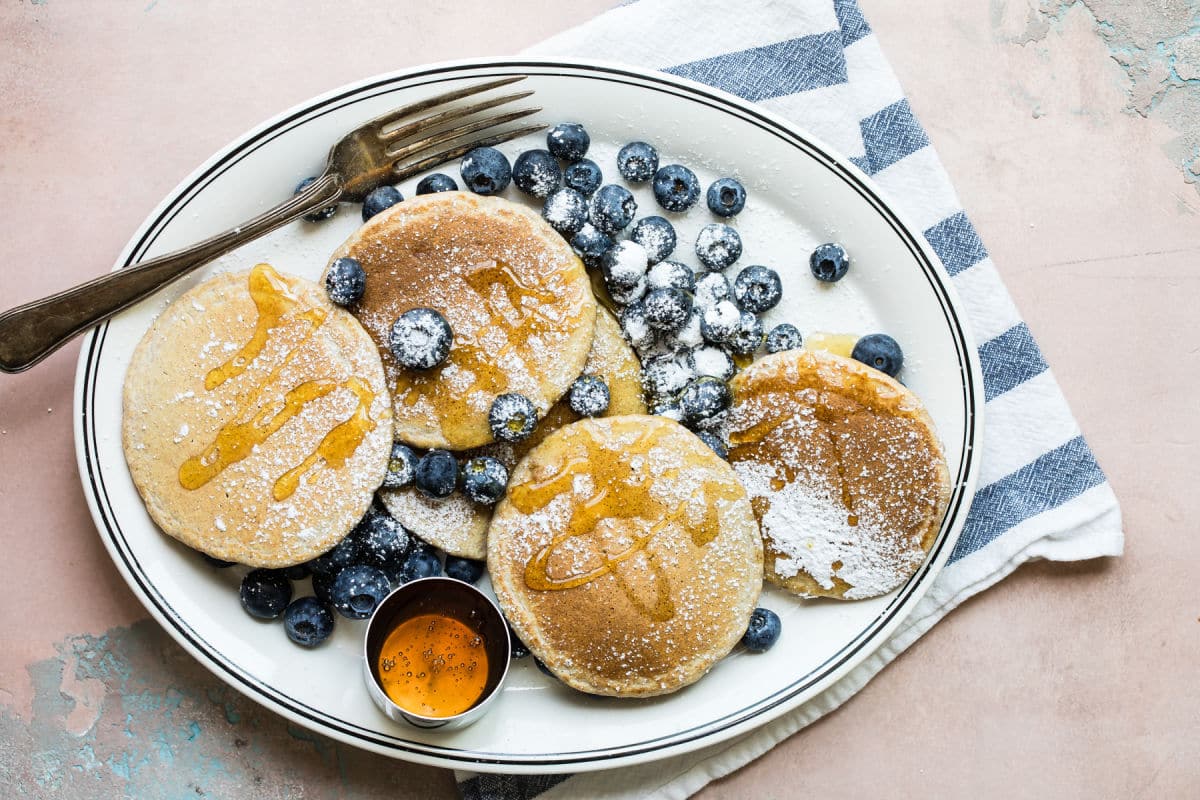 A stack of healthy pancakes with blueberries and powdered sugar.