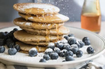 A stack of healthy pancakes with blueberries and powdered sugar.