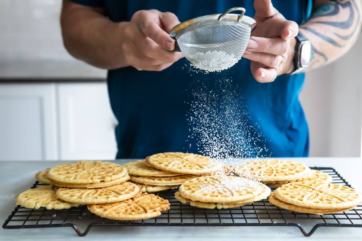 Dusting Pizzelle cookies with powdered sugar.