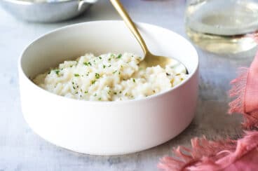 Risotto in a white bowl with a gold spoon.