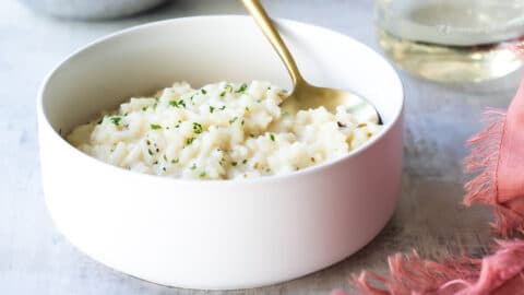 Risotto in a white bowl with a gold spoon.