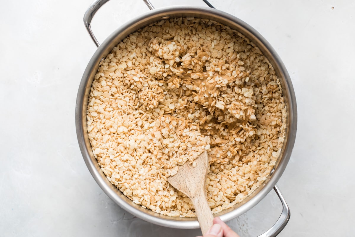 Stirring rice krispies into peanut butter filling for Scotcheroos.