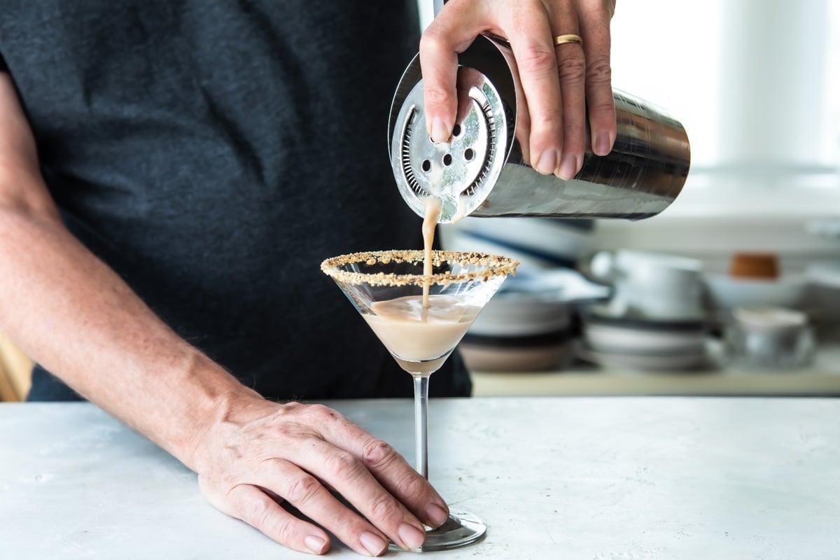 Pouring a S'mores Martini into a martini glass from a cocktail shaker.
