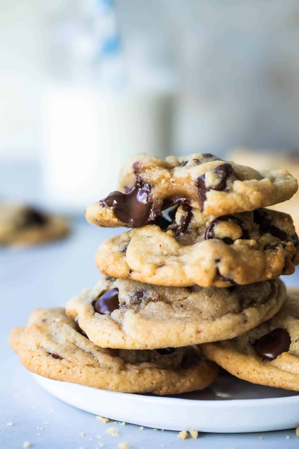 A stack of gooey chocolate chip cookies on a white plate.
