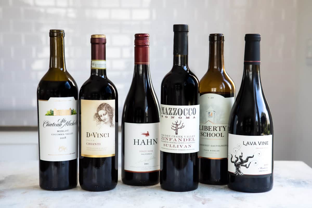 A collection of different kinds of red wines in bottles.