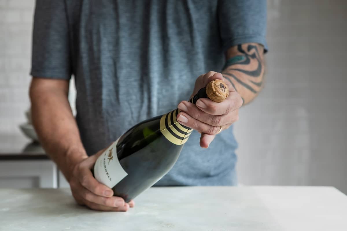 Removing the cork from a bottle of champagne.
