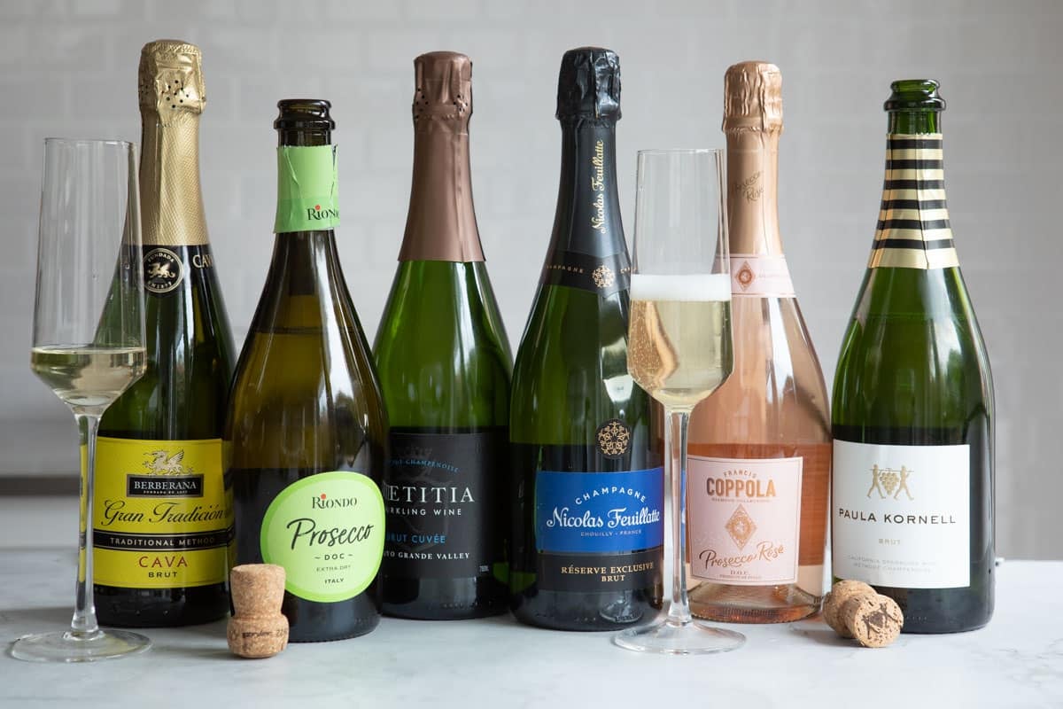 A collection of bottles of different kinds of sparkling wine.