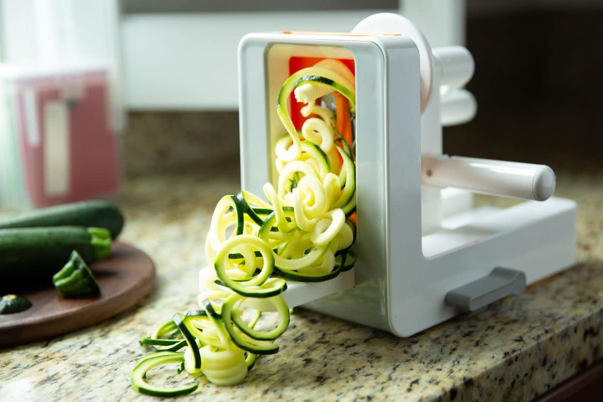 A zucchini being spiralized on an Oxo spiralizer.