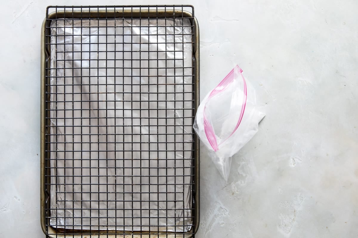 A baking rack over a baking sheet next to a ziploc bag of baking powder.
