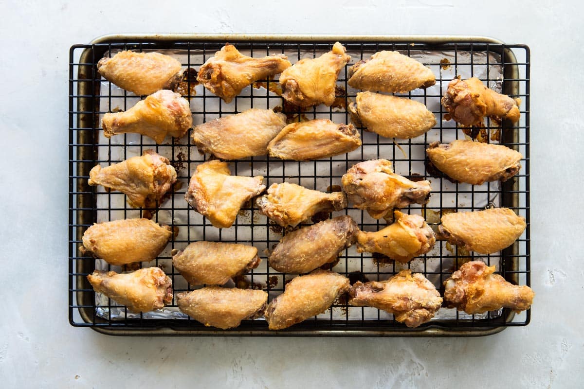 Wings on a baking rack over a baking sheet.