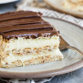 Slices of no-bake Chocolate Eclair Cake on white plates with forks.