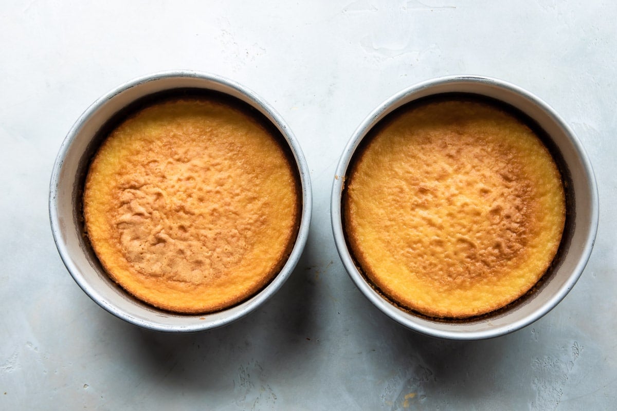 Two cake pans with vanilla cakes inside.